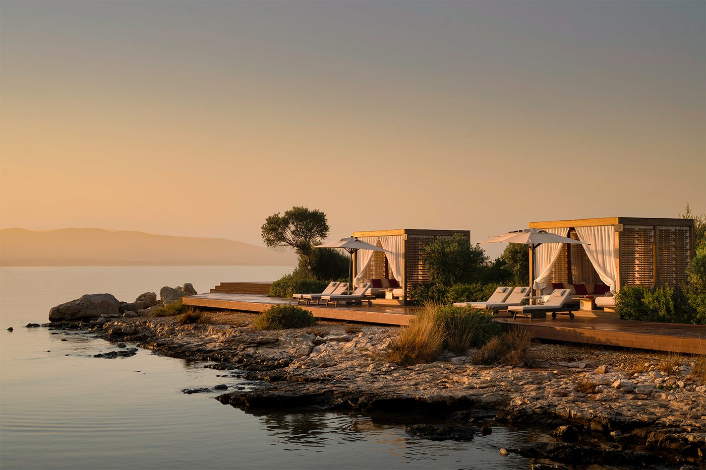 Two cabanas on the rocky shoreline in the last light