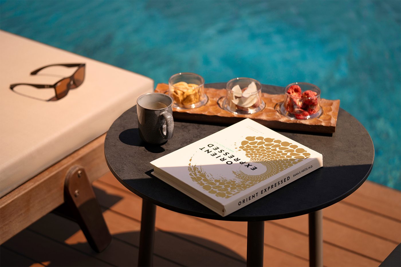 Side table by the pool with a coffee cup and a book