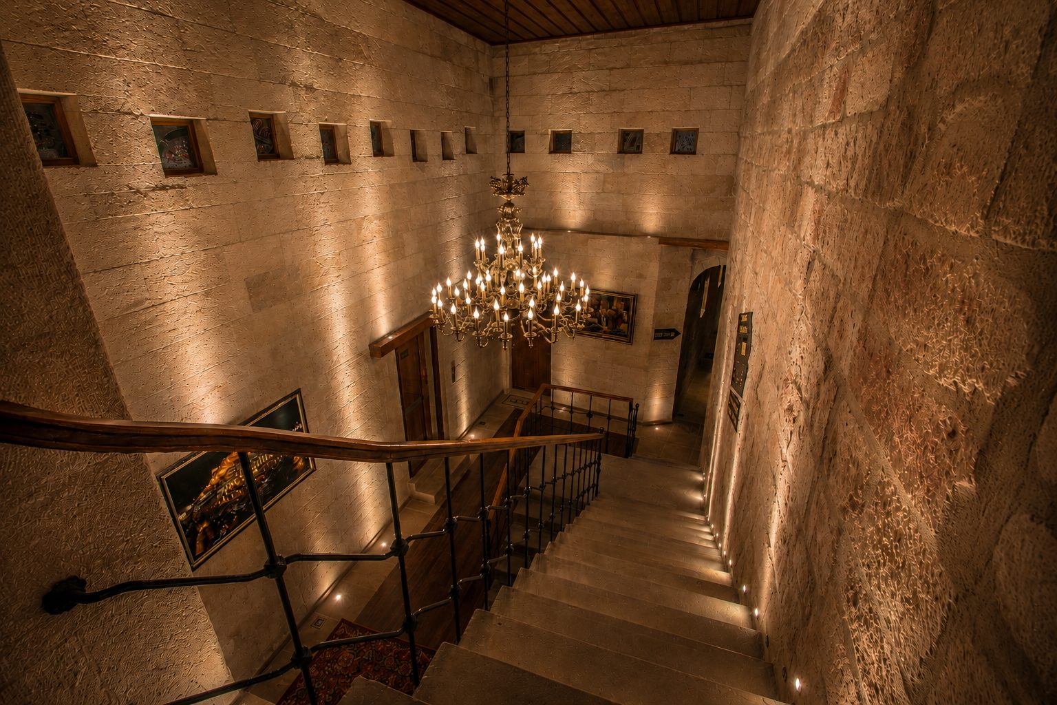 Stone staircase down to reception under a brass chandelier