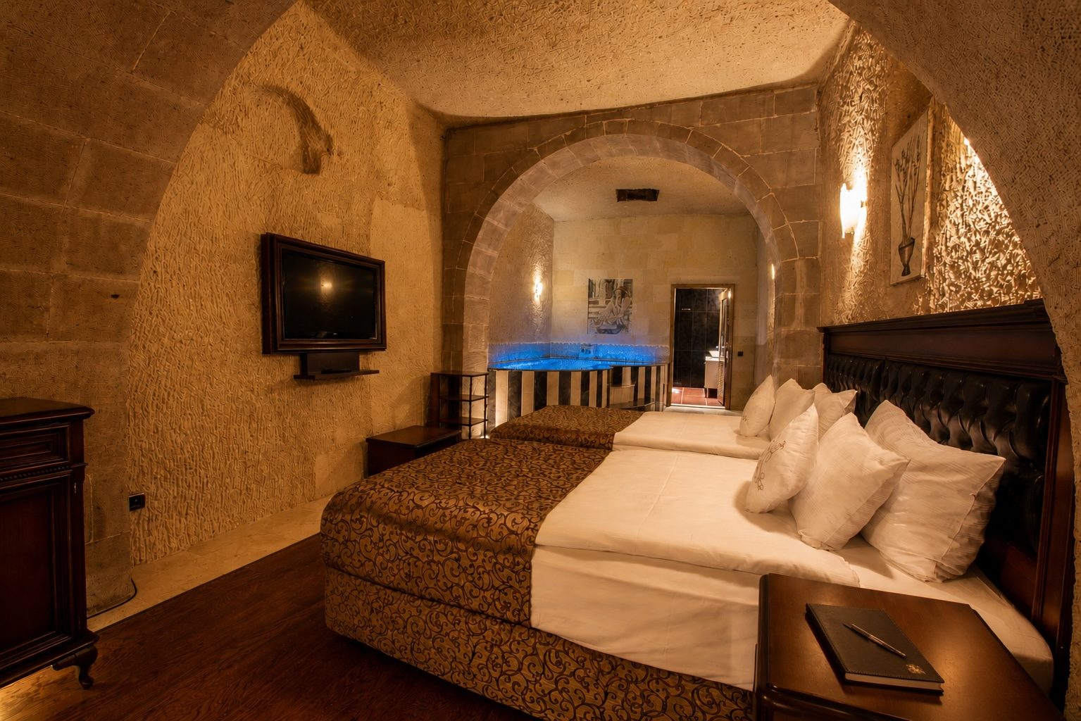 Deluxe cave room with a sunken pool behind the bed